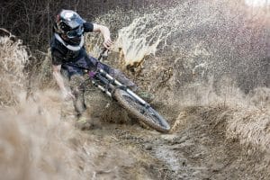 Mountainbiker mit Fullface-Helm im Schlamm