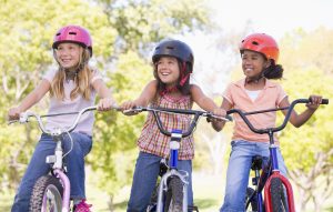 Drei Mädchen mit Fahrradhelmen und Rädern